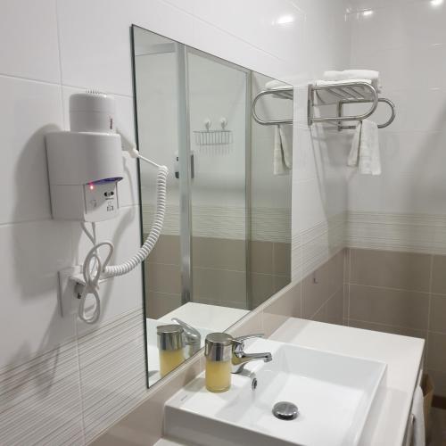 a white bathroom with a sink and a mirror at Cagaréus in Aveiro