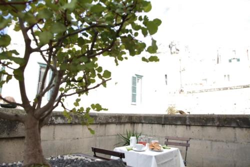 a table with a white table cloth sitting next to a tree at Le Malve Cave Retreat in Matera