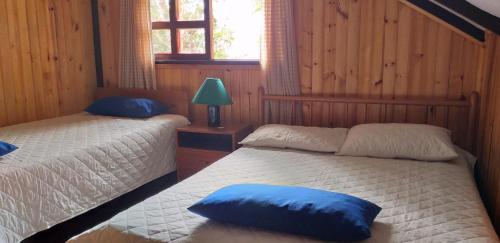 a bedroom with two beds with blue pillows on them at Bosque de Niebla Birding & Nature in Cali