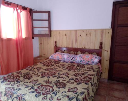 1 dormitorio con 1 cama con colcha de flores en Residencial ANAHATA en Capilla del Monte