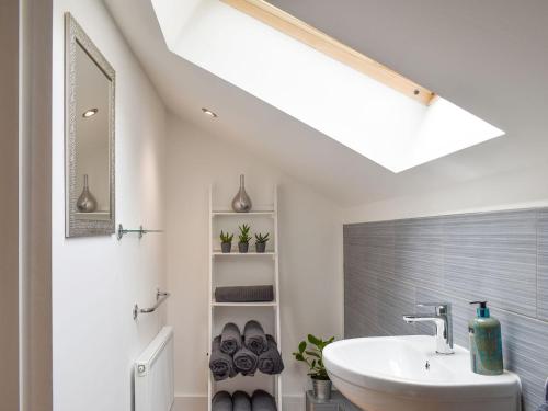 a bathroom with a white sink and a skylight at Perivale Lodge in Lydney