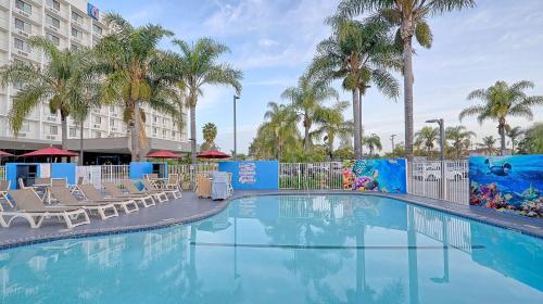 une piscine avec des chaises et des palmiers dans un hôtel dans l'établissement Motel 6-Los Angeles, CA - Los Angeles - LAX, à Inglewood