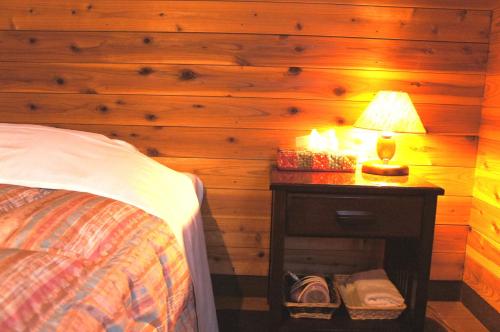 a bedroom with a bed and a lamp on a night stand at Ringo Lodge Hakuba in Hakuba