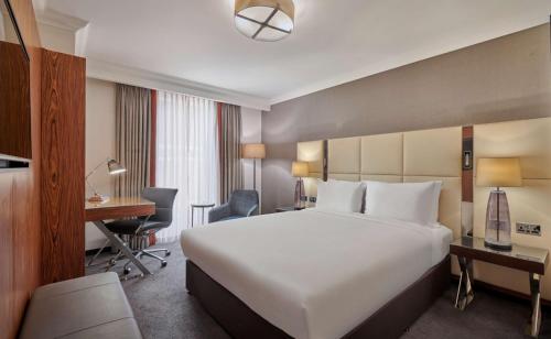 a hotel room with a large bed and a desk at Hyatt Regency London Albert Embankment in London