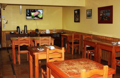 un restaurante con mesas y sillas de madera y TV en Hostal Rayen Centro, en Temuco