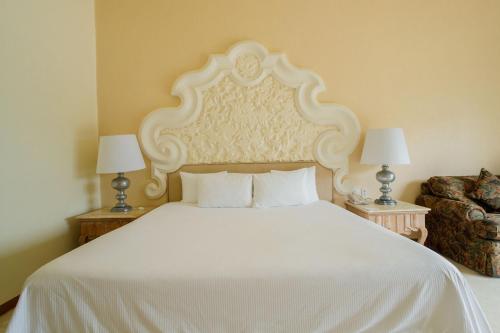 a bedroom with a large white bed and a chair at Quinta Real Acapulco in Acapulco