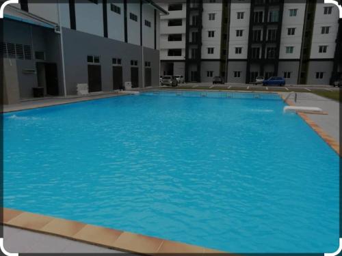 a large blue swimming pool in front of a building at Camelia Homestay in Seri Iskandar