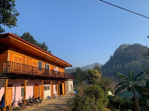 a building with a balcony and mountains in the background at Vĩ Homestay in Lao Cai