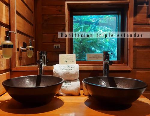 two sinks in a bathroom with a window at Aldea Naukana Posada Boutique in Pucón