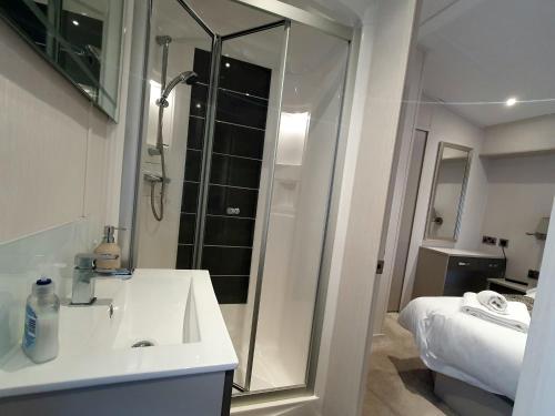 a white bathroom with a shower and a sink at Ash Retreat Hot Tub in Swarland
