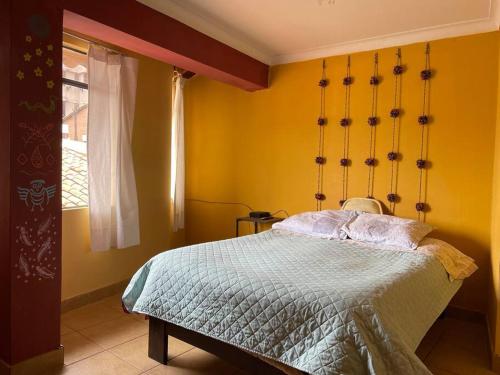1 dormitorio con cama y pared amarilla en Alojamiento de 2 Habitaciones con Baño Privado en Cuzco