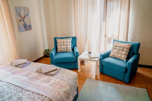 a bedroom with two blue chairs and a bed at Casa les Pomeretes in El Figaró