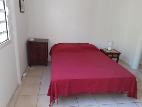 ein Bett mit einer roten Decke auf einem Zimmer in der Unterkunft Chez Françoise in Noumea