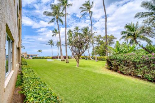 a lawn with palm trees and a building at Menehune Shores by Coldwell Banker Island Vacations in Kihei