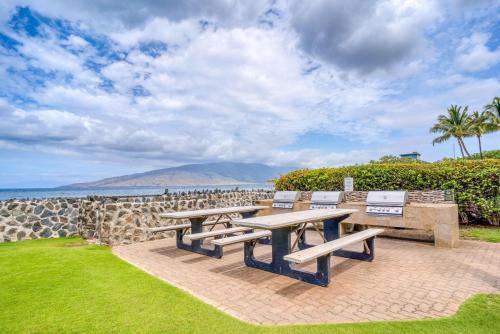 a patio with picnic tables and a view of the ocean at Menehune Shores by Coldwell Banker Island Vacations in Kihei