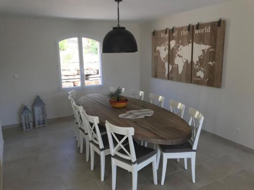 uma sala de jantar com uma mesa de madeira e cadeiras brancas em Contemporary villa with swimming pool em Emponse