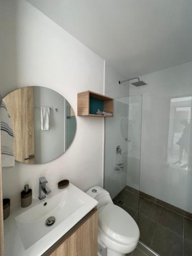 ein Badezimmer mit einem WC, einem Waschbecken und einem Spiegel in der Unterkunft Living Cartagena vista al mar y cuidad amurallada in Cartagena de Indias