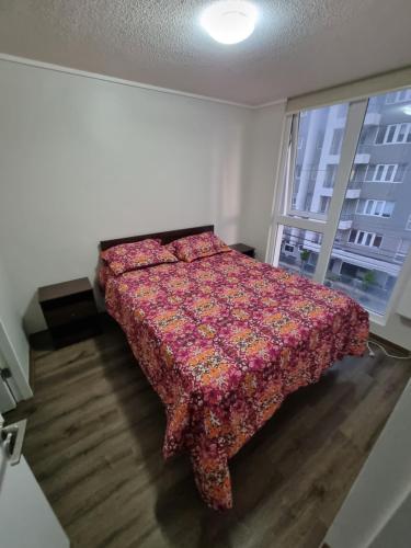 a bedroom with a bed with a floweredspread and a window at 407/ Precioso apartamento 1D+1B // JUMBO+CENTRO 5 MIN in Puerto Montt