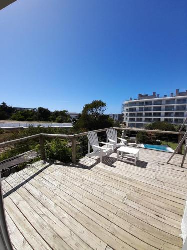a wooden deck with two chairs and a pool at Casa Bikini in Punta del Este