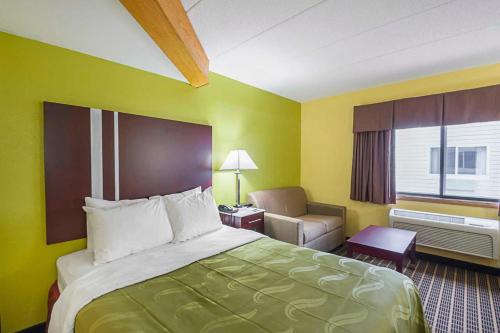 um quarto de hotel com uma cama e uma cadeira em Quality Inn & Suites Harrington em Harrington