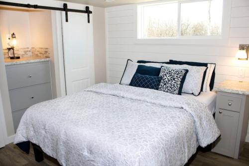a white bedroom with a bed and a window at Twin Lakes Tiny Homes of Okmulgee in Okmulgee