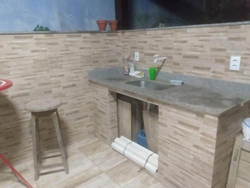 a kitchen with a counter with a sink and a stool at Suite Aconchegante 01 in Saquarema
