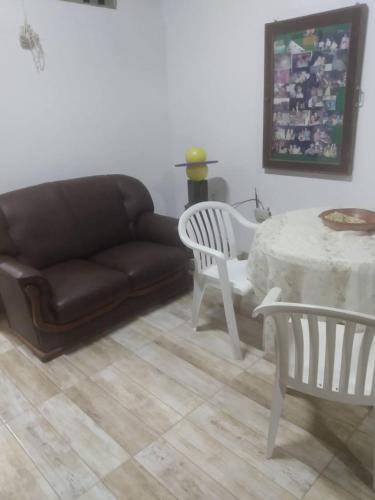 a living room with a couch and a table and chairs at Suite Aconchegante 01 in Saquarema