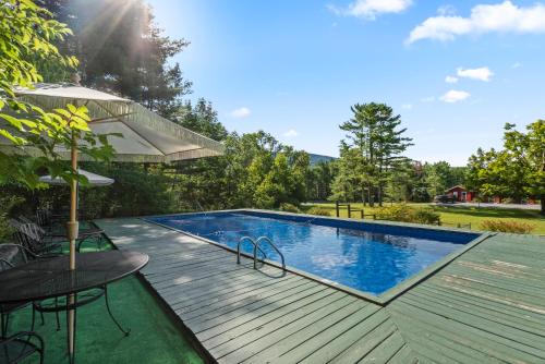 a swimming pool on a wooden deck with a table and an umbrella at North Shire Lodge in Manchester