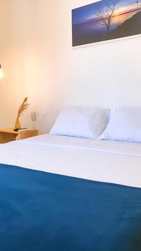 1 dormitorio con cama blanca y manta azul en Tatu Suítes, en Porto de Pedras