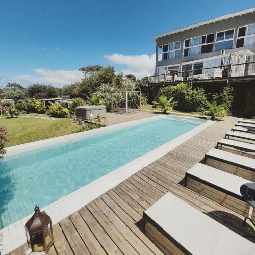 a swimming pool with a wooden deck and a building at Casa Bikini in Punta del Este