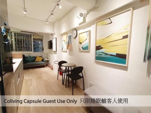 a living room with a table and paintings on the wall at L'etoile Hella Inn in Hong Kong
