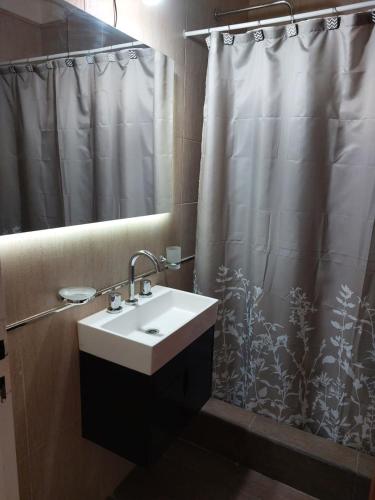 a bathroom with a sink and a shower curtain at Departamento a 10 metros de la Catedral y plaza principal, con vista desde el balcon in San Fernando del Valle de Catamarca