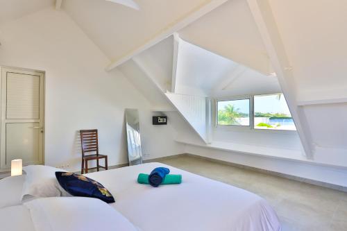 ein weißes Schlafzimmer mit einem Bett und einem Fenster in der Unterkunft Modern Beach Villa 1150 in Saint Martin