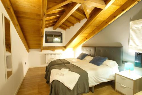 a bedroom with a large bed and wooden ceilings at Cuencaloft La Plazeta in Cuenca
