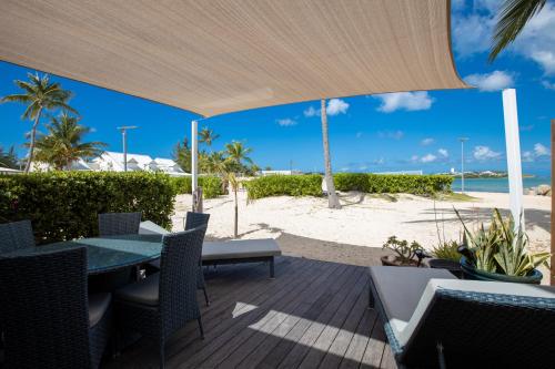 a patio with a table and chairs and the beach at Modern Beach Villa 1150 in Baie Nettle