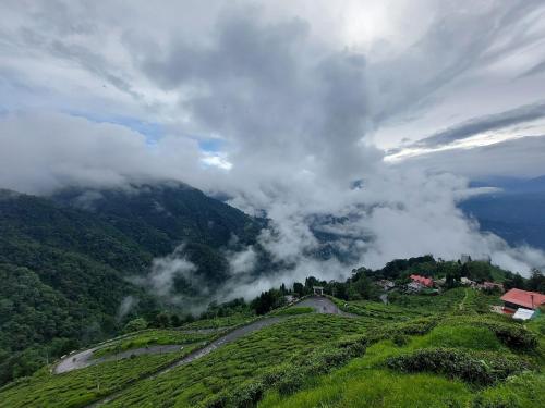 a view of a mountain with clouds in the sky at Bloomfield Farmhouse and Eco-Resort in Darjeeling