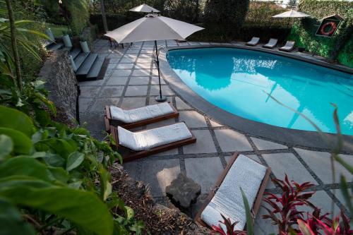 a swimming pool with two lounge chairs and an umbrella at Hotel Grand Vista Cuernavaca in Cuernavaca