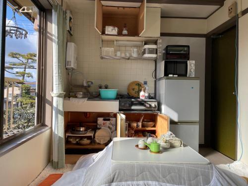 a small kitchen with a table and a refrigerator at Kyoto Wakouan Retro Stay in Kinugasa