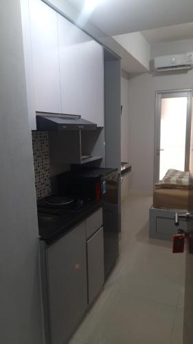 uma cozinha com armários brancos e uma cama num quarto em Transpark juanda bekasi em Padurenan