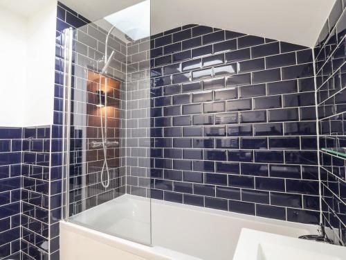 ein Badezimmer mit blau gefliesten Wänden und einer Badewanne in der Unterkunft Poppy Cottage in Southwold