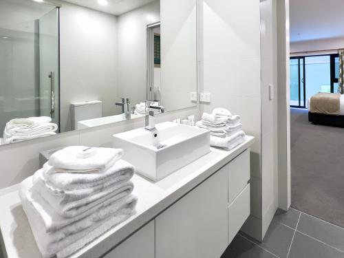 La salle de bains blanche est pourvue d'un lavabo et d'un miroir. dans l'établissement Sixty Six Boutique Apartments, à Hobart