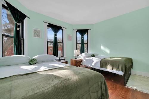 a bedroom with two beds and two windows at Green N' Groovy in the Heart of East Rock Near DT, Yale in New Haven