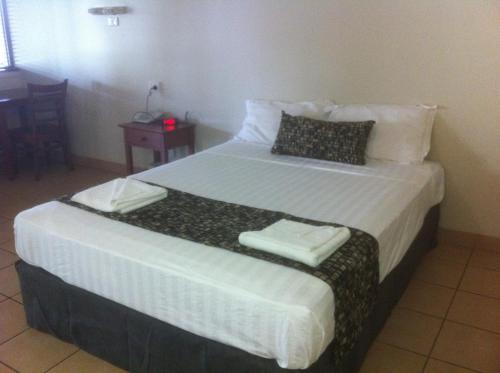 a hotel room with a white bed and a white comforter at Black Nugget Hotel Motel in Moranbah