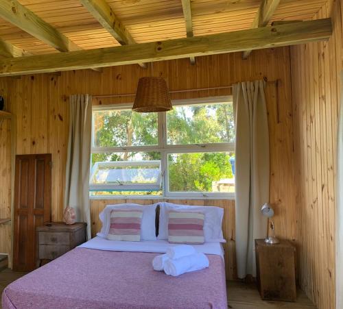 1 dormitorio con ventana grande y cama en La Marencoche - Casa de Madera en Punta Rubia, en La Paloma