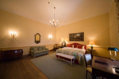 a bedroom with a bed and a chair and a table at Hotel Château Bela in Belá