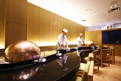 two chefs are preparing food in a restaurant at Keio Plaza Hotel Tokyo in Tokyo