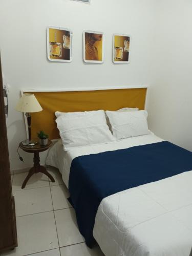 sypialnia z łóżkiem i stołem oraz obrazami na ścianie w obiekcie Hostel Palma de Leão w mieście Salvador