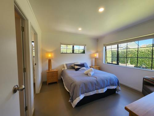 a bedroom with a bed and a large window at Hahei Garden Sanctuary in Hahei