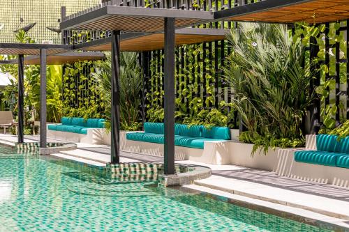 a pool with blue lounge chairs next to a swimming pool at OUTRIGGER Surin Beach Resort in Surin Beach