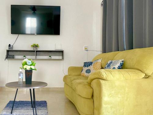 a living room with a yellow couch and a tv at Casa el conquistador/ExcelenteUbicación/2Hab/Wifi in Mérida